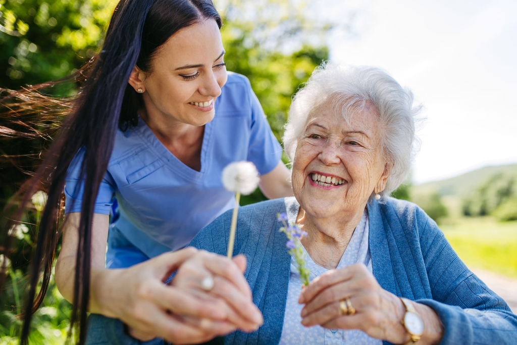 Caregiver smiling with an elderly woman outdoors